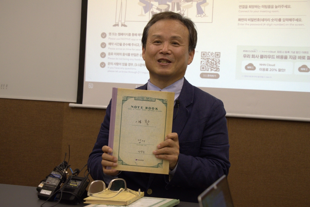 사진 설명 시작. 단국대 우정권 교수가 박목월 육필시 실물 복각본 중 생활 편을 들고 설명 중이다. 사진 설명 끝.