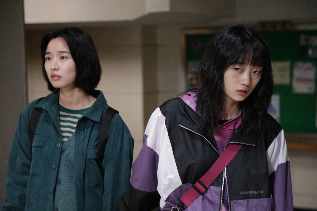 사진 설명 시작. 왼쪽부터 나미와 선우가 서 있다. 둘은 화면 바깥의 어딘가를 바라보고 있다. 사진 설명 끝.