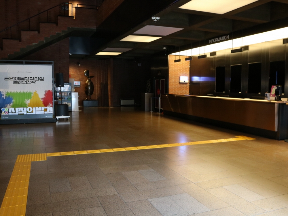 사진 설명 시작. 공연장 로비 출입문에 노란 점자 보도블록이 깔려 매표소까지 이어지고 있다. 사진 설명 끝.