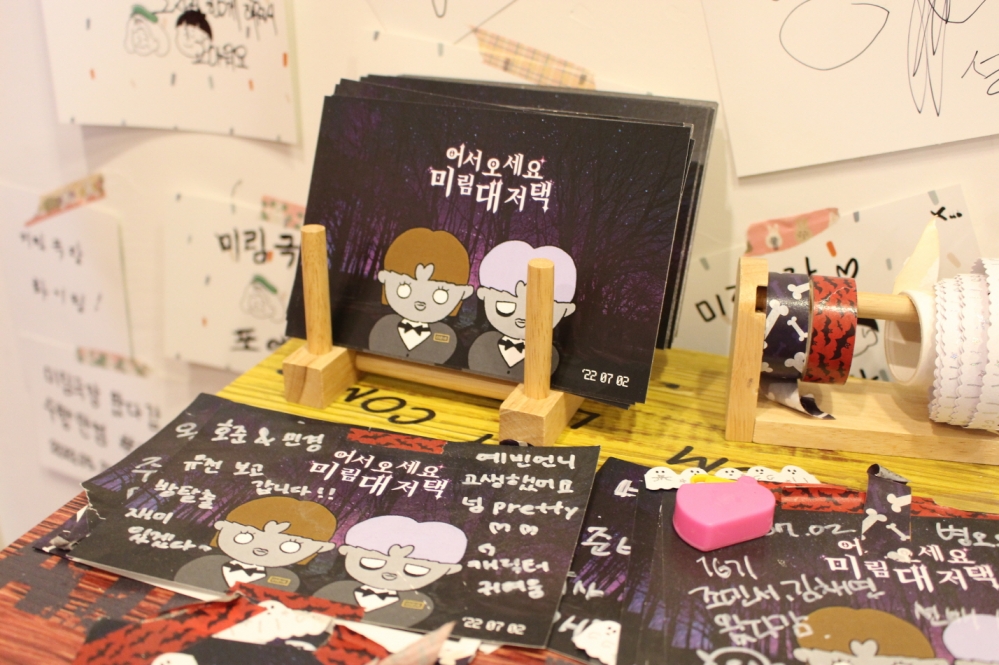 사진 설명 시작. 호러영화제 카드들이다. 어두운 숲을 배경으로 회색 피부의 여성과 남성 캐릭터가 정장을 입은 채 서있다. 그 위로