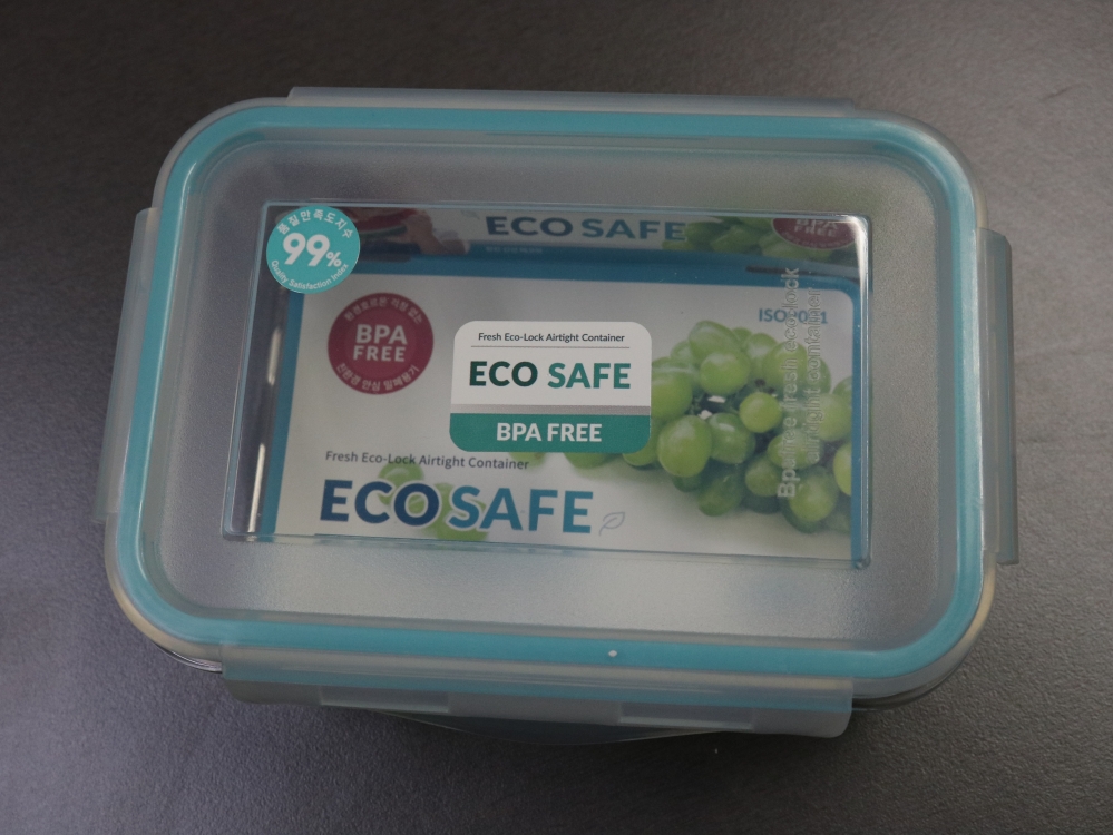 사진 설명 시작. 테두리가 하늘색인 뚜껑이 덮힌 직육면체 모양 밀폐용기가 확대되어 있다. 넓은 뚜껑 위에는