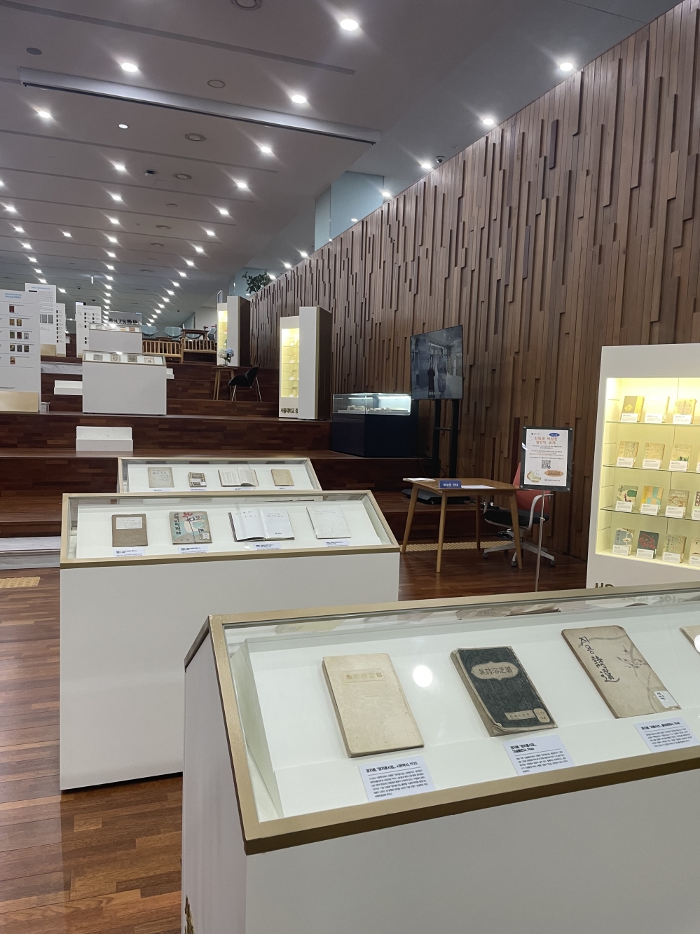 사진 설명 시작. 도서관 계단에 다양한 책들이 전시되어 있다. 책에 대한 설명과 문학에 대한 설명들이 제시되고 있다. 사진 설명 끝.