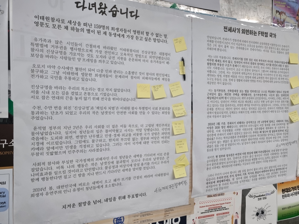 사진 설명 시작. 서울대 중앙도서관 통로 게시판에 두 개의 벽보가 붙어 있다. 다녀왔습니다라는 제목의 벽보와 전세사기 외면하는 F학점 국가라는 제목의 벽보이다. 벽보에는 마지막줄에 투표를 독려하는 내용이 쓰여 있고, 곳곳에 노란 포스트잇들이 같이 붙어 있다. 사진 설명 끝.