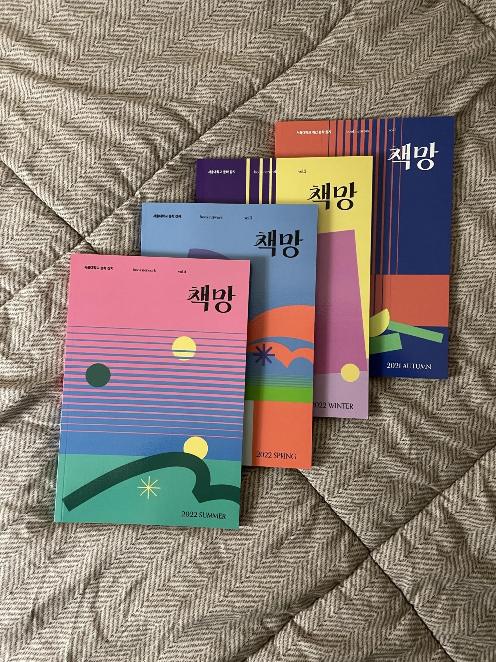 사진 설명 시작. 회색 이불 위에