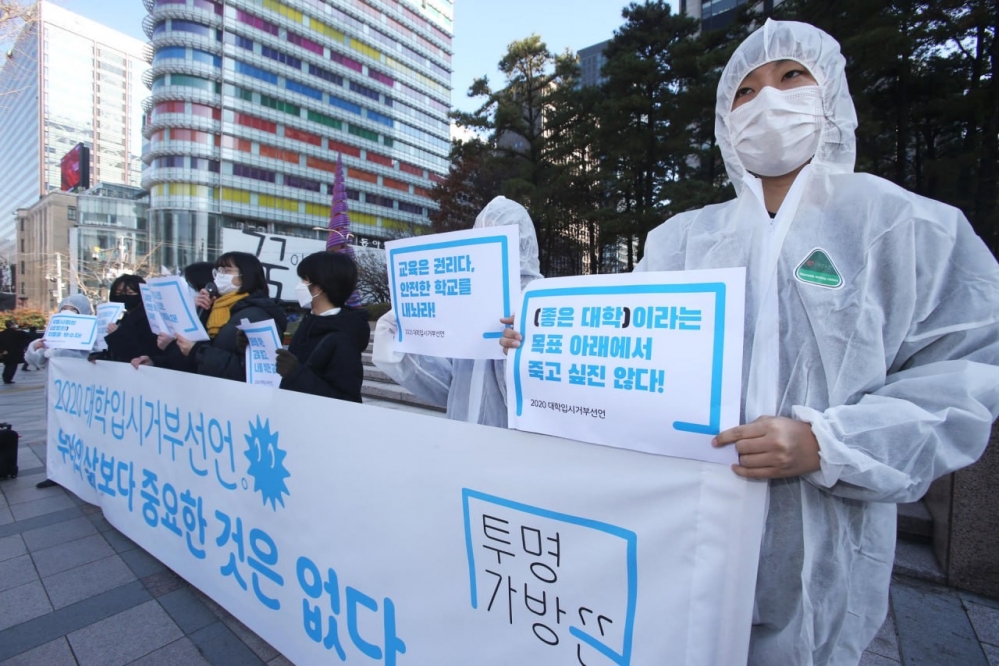 사진 설명 시작. 약 7명의 사람이 옆으로 늘어서 서 있다. 사람들은 손에