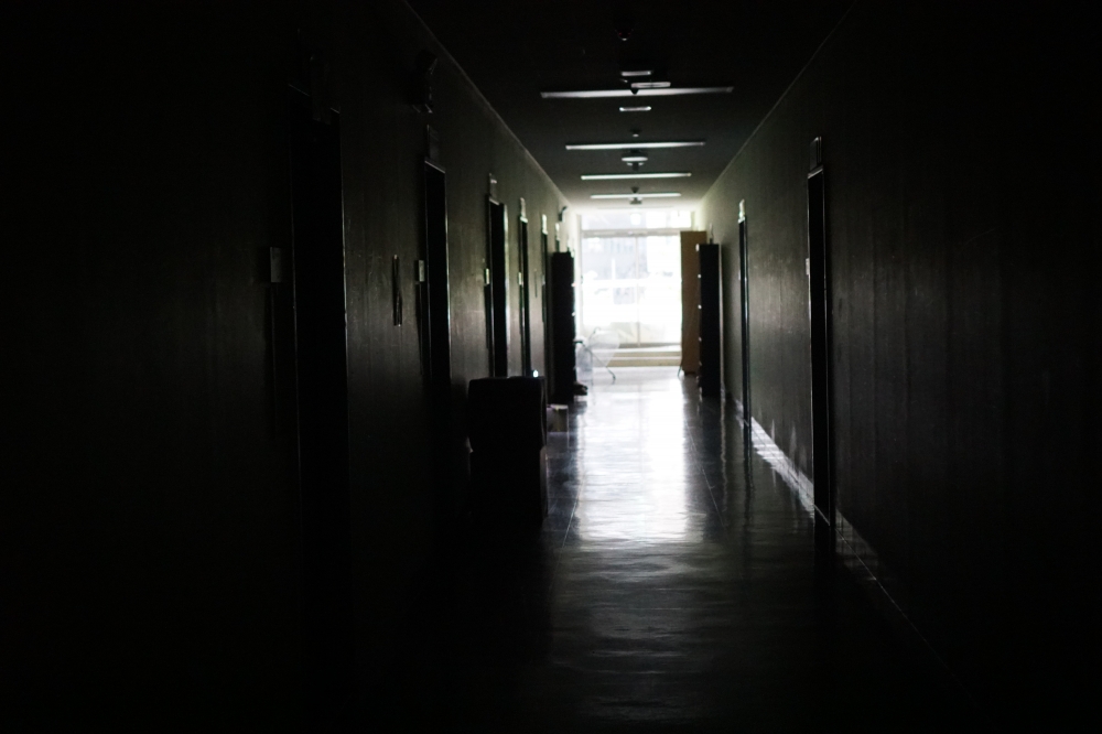 사진 설명 시작. 불 꺼진 복도이다. 복도 끝에 투명한 우산이 있다. 사진 설명 끝.