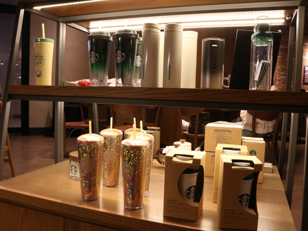 사진 설명 시작. 은은한 노란빛의 조명 아래 두 칸으로 구성된 진열대가 놓여있다. 그 안에 스타벅스의 텀블러 MD 상품들이 진열돼 있다. 사진 설명 끝.