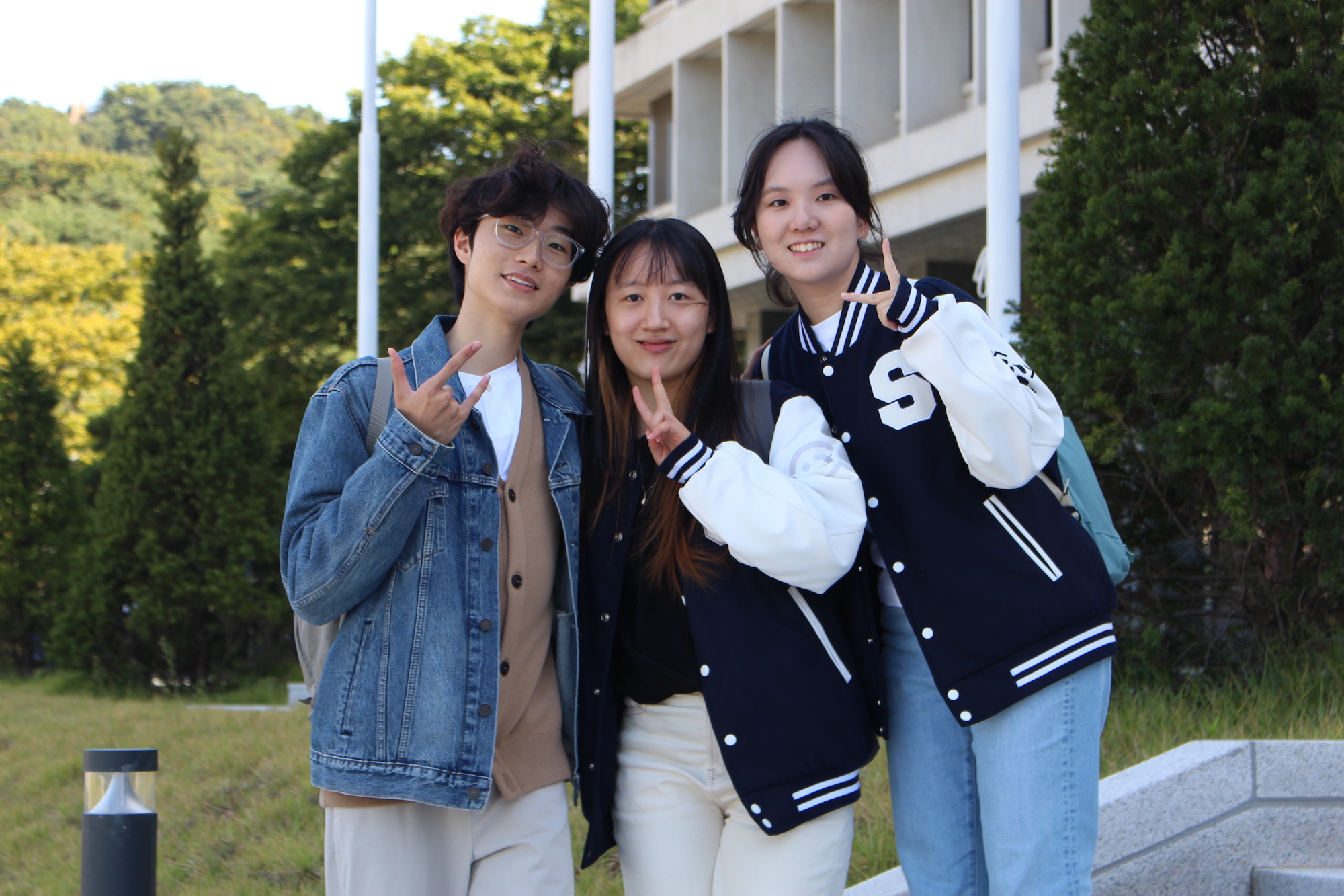 사진 설명 시작. 교정을 배경으로, 세 인터뷰이가 카메라를 바라보고 있는 단체사진이다. 사진 설명 끝.