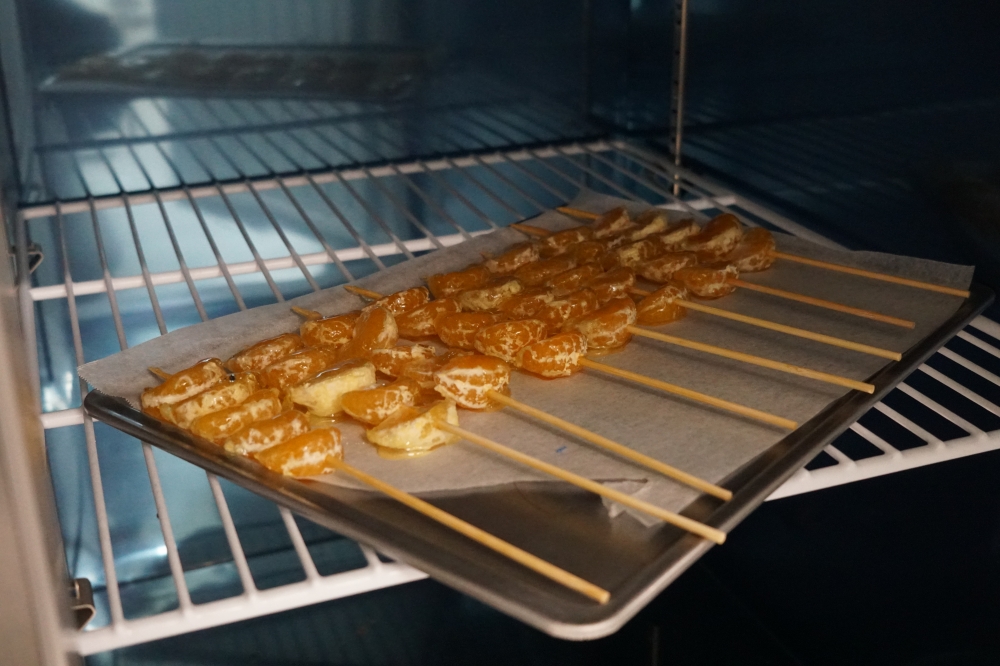 사진 설명 시작. 주방의 건조대 안에 귤과 어묵꼬치로 만들어진 탕후루가 건조되고 있다. 사진 설명 끝.