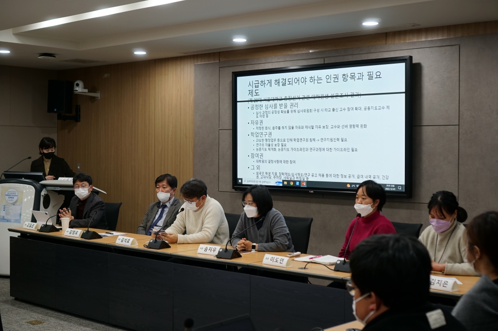 사진 설명 시작. 강의실 앞쪽에 연구진들이 앉아 있다. 연구진들 뒤에 있는 tv에는 인식조사 결과를 설명하는 프레젠테이션이 띄워져 있다. 사진 설명 끝.