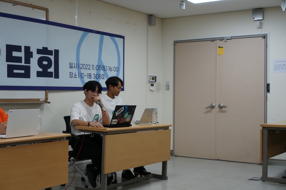 사진 설명 시작. 강의실 앞에 놓인 책상에 공명 선본의 두 후보가 앉아 있다. 이준서 정후보가 마이크를 들고 발언하고 있다. 사진 설명 끝.