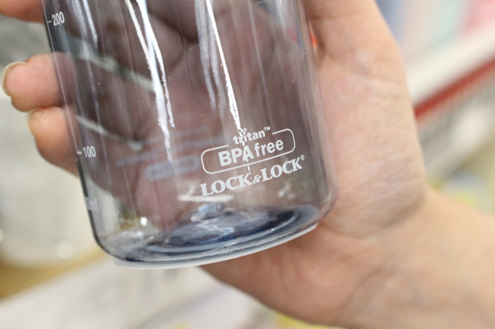 사진 설명 시작. 투명한 원기둥 모양 플라스틱 용기를 손으로 쥐고 있다. 용기에