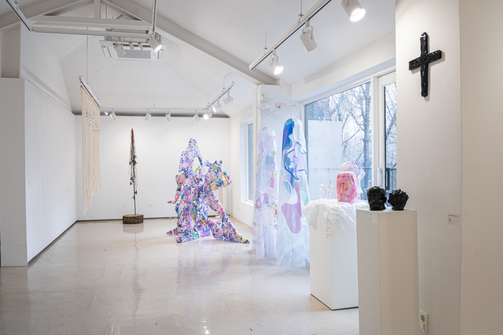 사진 설명 시작. 암실의 제3회 기획전 『춤추는 사람들은 안개 속에서』 전시장의 전경 사진이다. 가장 안쪽에서부터 여러개의 밧줄이 걸린 작품, 나무 밑동에 철기둥이 꽂혀있고 그 끝에 여러 철실이 매달린 작품, 사람의 움직임을 여러 색으로 표현한 조형물이 위치해있다. 그 앞에는 천장에 매달린 천 2개로 구성된 작품, 분홍색의 조형물, 기도하는 손과 사람 얼굴을 표현한 조형물, 그 위에 십자가가 위치해있다. 사진 설명 끝.