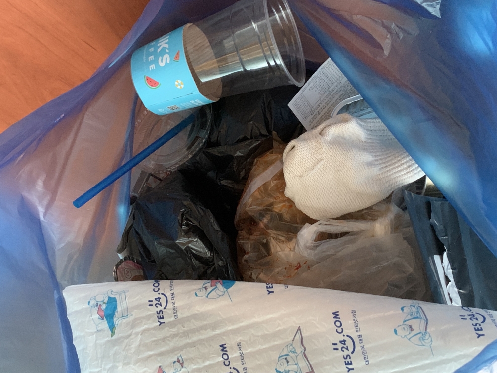 사진 설명 시작. 플라스틱을 배출하는 봉투 안에 일반쓰레기 등 다른 쓰레기들이 들어있다. 사진 설명 끝.