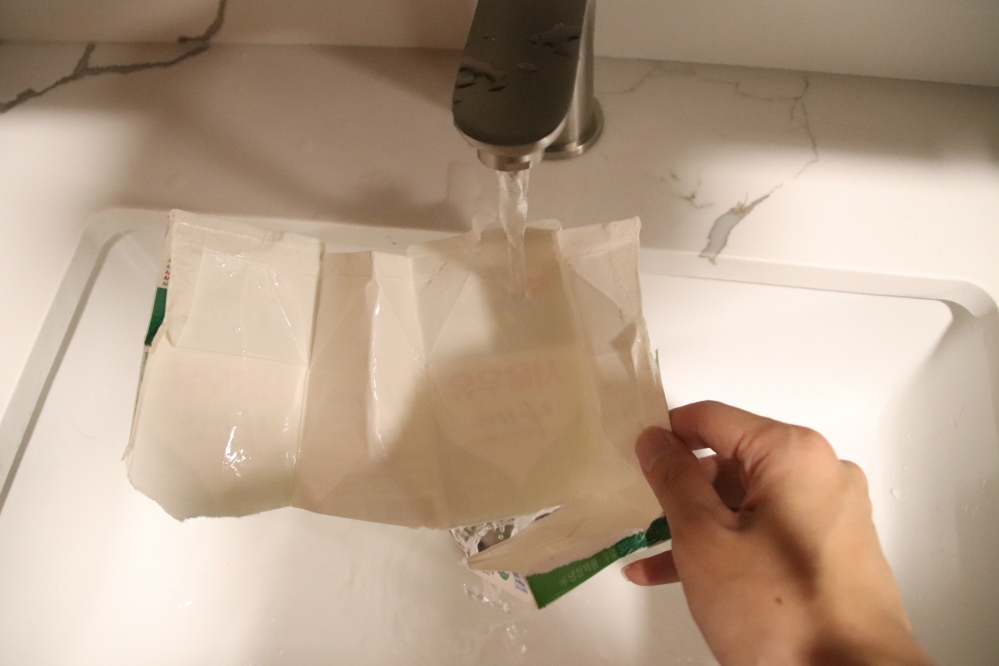 사진 설명 시작. 우유팩 내부를 물로 씻고 있다. 사진 설명 끝.