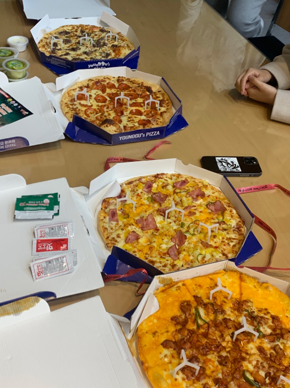 사진 설명 시작. 피자 4판이 책상 위에 놓여있다. 사진 설명 끝.