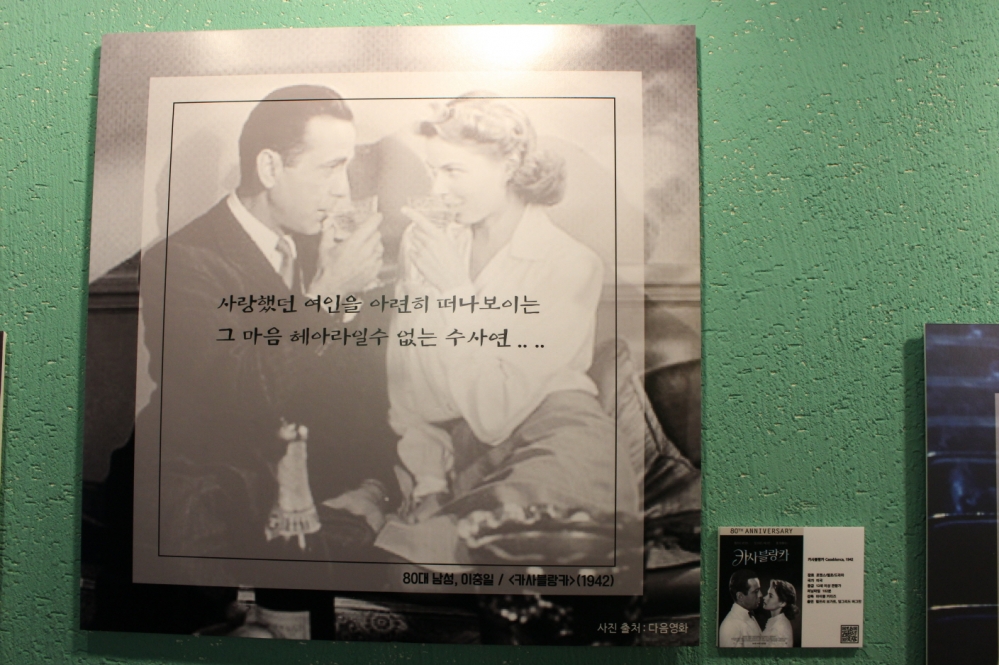 사진 설명 시작. 서로를 바라본채 술잔을 입에 대고 있는 두 남녀의 흑백 사진을 배경으로