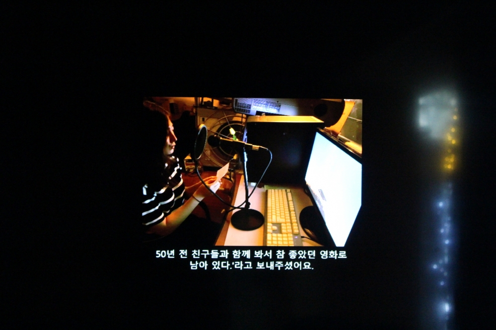 사진 설명 시작. 한 여성이 모니터를 앞에 둔 채 마이크에 대고 사연을 읽고 있다. 그 아래