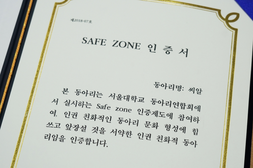 사진 설명 시작. 흰 배경에 금박 테가 있는 종이에 제2018-17호 safe zone 인증서 동아리명 씨알 본 동아리는 서울대학교 동아리연합회에서 실시하는 safe zone 인증제도에 참여하여, 인권 친화적인 동아리 문화 형성에 힘쓰고 앞장설 것을 서약한 인권 친화적 동아리임을 인증합니다. 라고 써있다. 사진설명 끝.