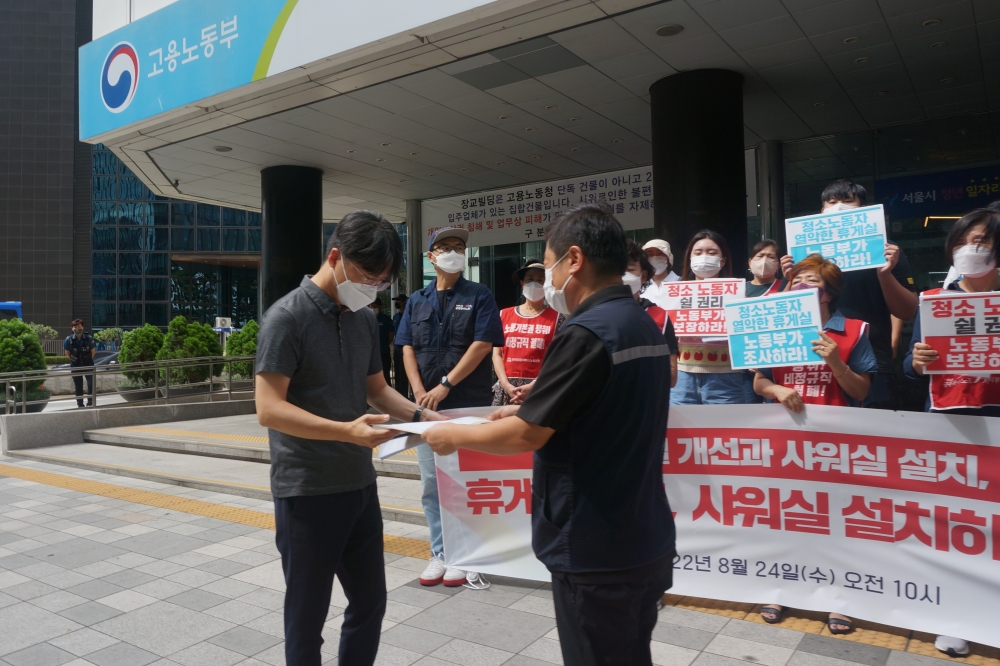 사진 설명 시작. 현수막과 피켓을 든 기자회견 참여자를 뒤로 하고 공공운수노조 지부장이 고용노동부 관계자에게 요구안을 담은 서류를 전달하고 있다. 사진 설명 끝.