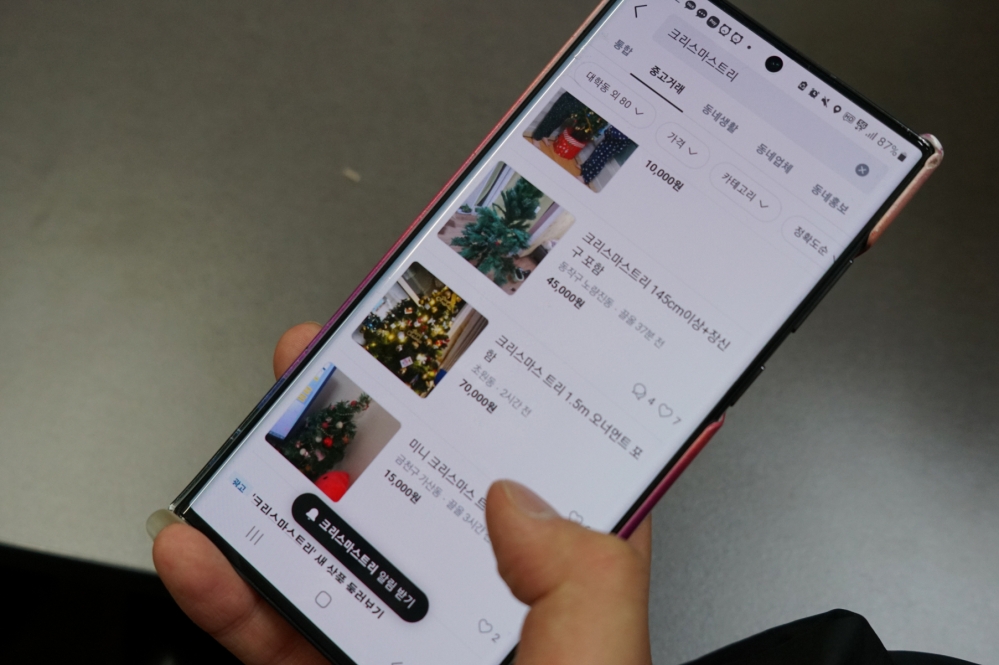 사진 설명 시작. 중고 거래 어플을 통해 크리스마스트리를 고르고 있다. 사진 설명 끝.
