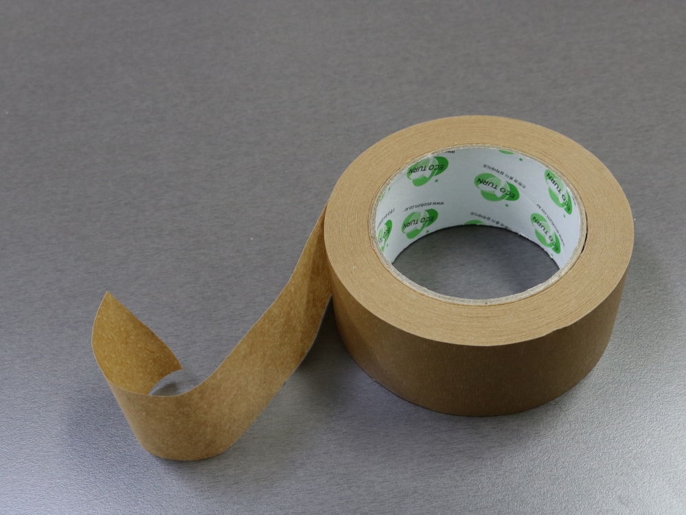 사진 설명 시작. 옅은 갈색의 대형 종이테이프가 끝부분이 10cm 가량 떼어진 채 놓여 있다. 테이프 심의 안쪽 부분에