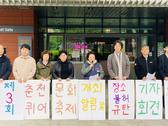 사진 설명 시작. 여러 연령의 사람들이 흰색 바탕의 플랜카드를 들고 서 있다. 플랜카드의 문구는 왼쪽부터