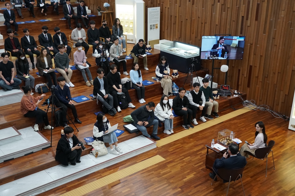 사진 설명 시작. 관정마루 계단에 학생들이 앉아 있다. 계단 앞쪽에는 유홍림 총장과 사회자가 앉아 있다. 사진 설명 끝.