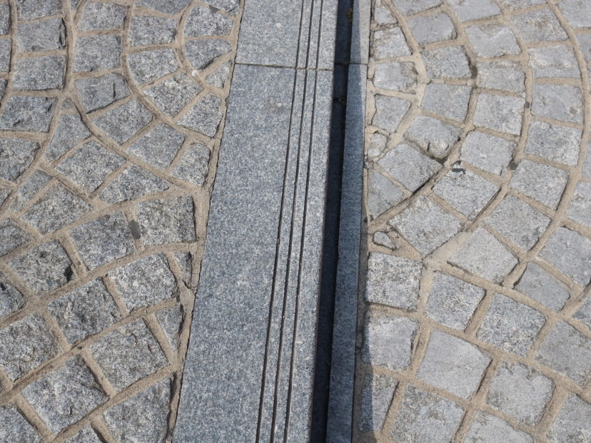 사진 설명 시작. 아르코예술극장 입구의 계단과 휠체어램프 포석을 확대하여 찍은 사진이다. 계단의 포석은 울퉁불퉁하지만, 휠체어램프의 포석은 갈아내어 매끈하다. 사진 설명 끝.