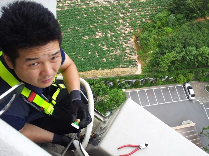 삼성전자서비스 수리기사들은 안전사고에도 노출돼 있다. 사진은 삼성전자서비스 기사가 아파트 고층 난간에 매달려 에어컨을 수리하는 모습. ⓒ삼성전자서비스지회.jpg