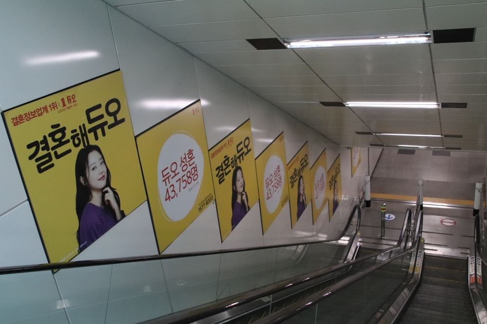 사진 설명 시작. 에스컬레이터 옆 벽면에 결혼해듀오 광고가 주루룩 붙어있다. 올라가거나 내려갈 때 계속해서 광고에 노출될 수 밖에 없다. 사진 설명 끝.