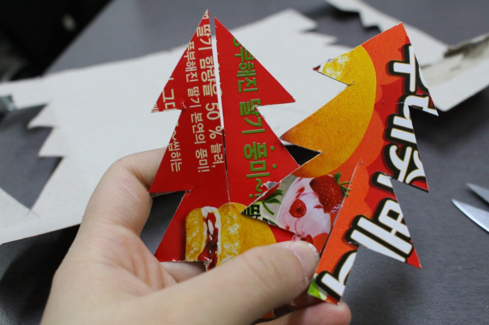 사진 설명 시작. 과자 상자를 트리 모양으로 2개 잘라낸 후 가운데에 홈을 만든 모습이다. 사진 설명 끝.