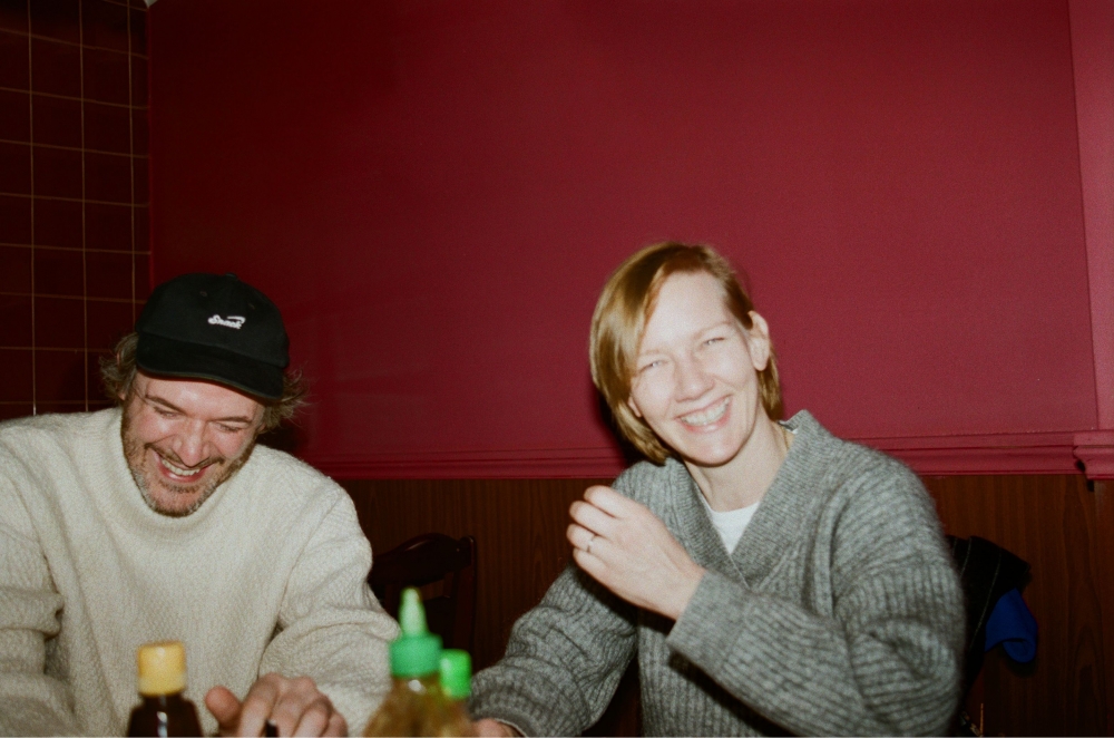 사진 설명 시작. 플래시를 터뜨려 찍은 사진이다. 붉은 벽지가 붙은 방 안에서 산드라와 사뮈엘이 웃고 있다. 사진 설명 끝.