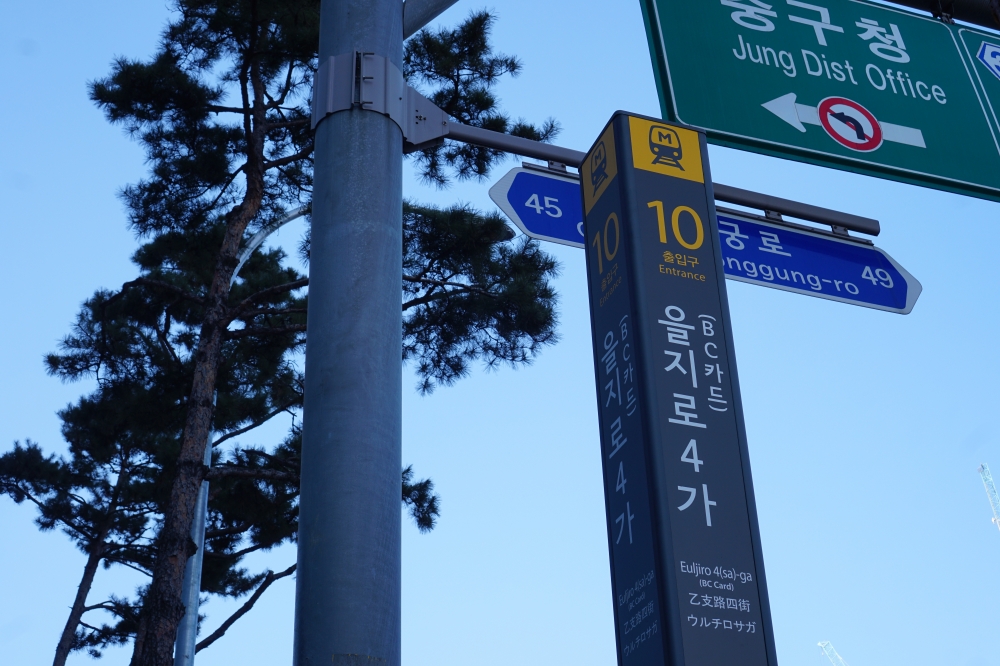 사진 설명 시작. 가로등과 지하철 역 팻말이 화면 가운데 나란히 보인다. 가로등은 오른쪽에, 팻말은 왼쪽에 있다. 팻말은 이 곳이 BC카드역이 새로 병기된 을지로4가역 10번 출구임을 설명하고 있다. 사진 설명 끝.