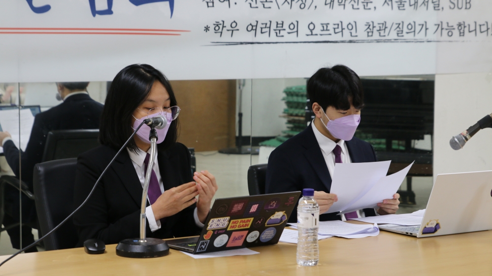 책상에 앉아있는 김지은 정후보와 전현철 부후보. 두 사람은 양복차림에 보라색 넥타이, 연보라색 마스크를 착용하고 있다. 책상에는 후보자 각각 마이크와 노트북이 놓여있다.