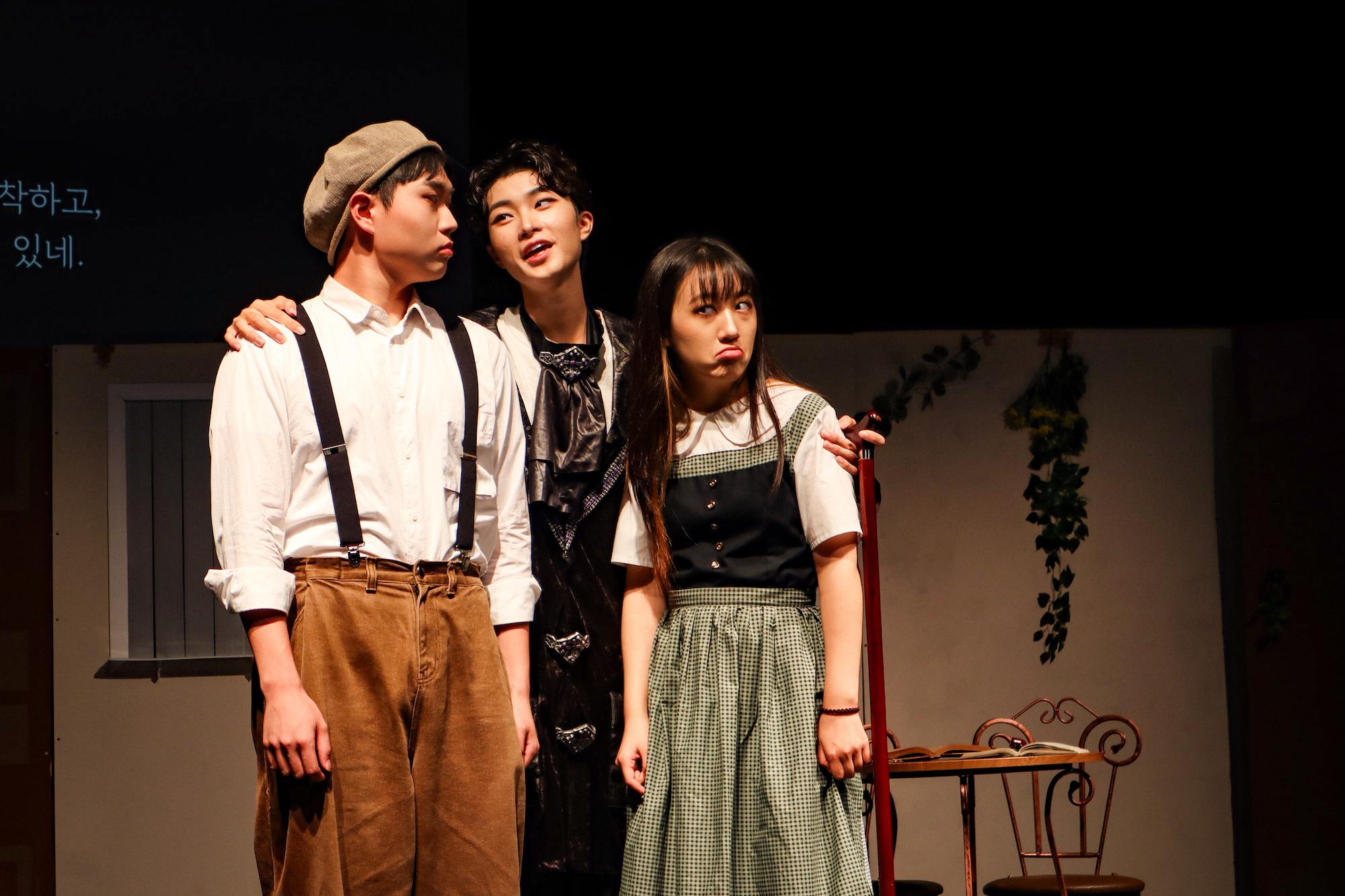 사진 설명 시작. 세 명의 배우들이 무대에서 연기를 하고 있다. 사진 설명 끝.