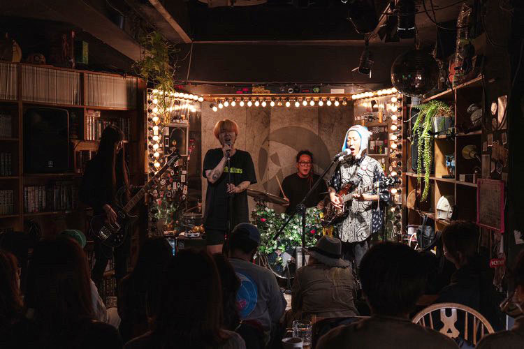 사진 설명 시작. 어두운 조명의 무대에서 밴드 빌리카터의 멤버 네 명이 공연하고 있다. 왼쪽부터 베이스 연주자, 보컬, 드럼 연주자, 기타 연주자가 공연 중이다. 사진 아래에는 관람 중인 관객들이 앉아있다. 사진 설명 끝.