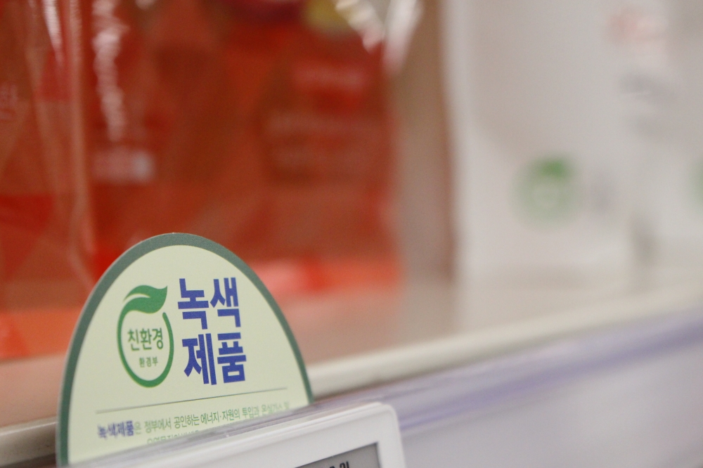 사진 설명 시작. 세제의 친환경 마크가 크게 확대되어 찍혀 있다. 마크에는 파란 글씨로 녹색 제품이라고 쓰여 있다. 사진 설명 끝.