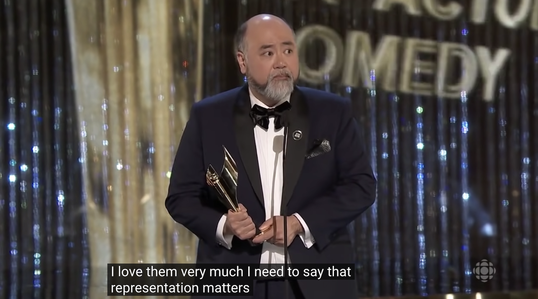 사진 설명 시작. 정장 차림의 한 남성이 트로피를 들고 마이크 앞에 서있다. 수상소감을 발표하는 모습이다. 자막으로는 ‘I love them very much. I need to say that representation matters’라고 적혀 있다. 사진 설명 끝.
