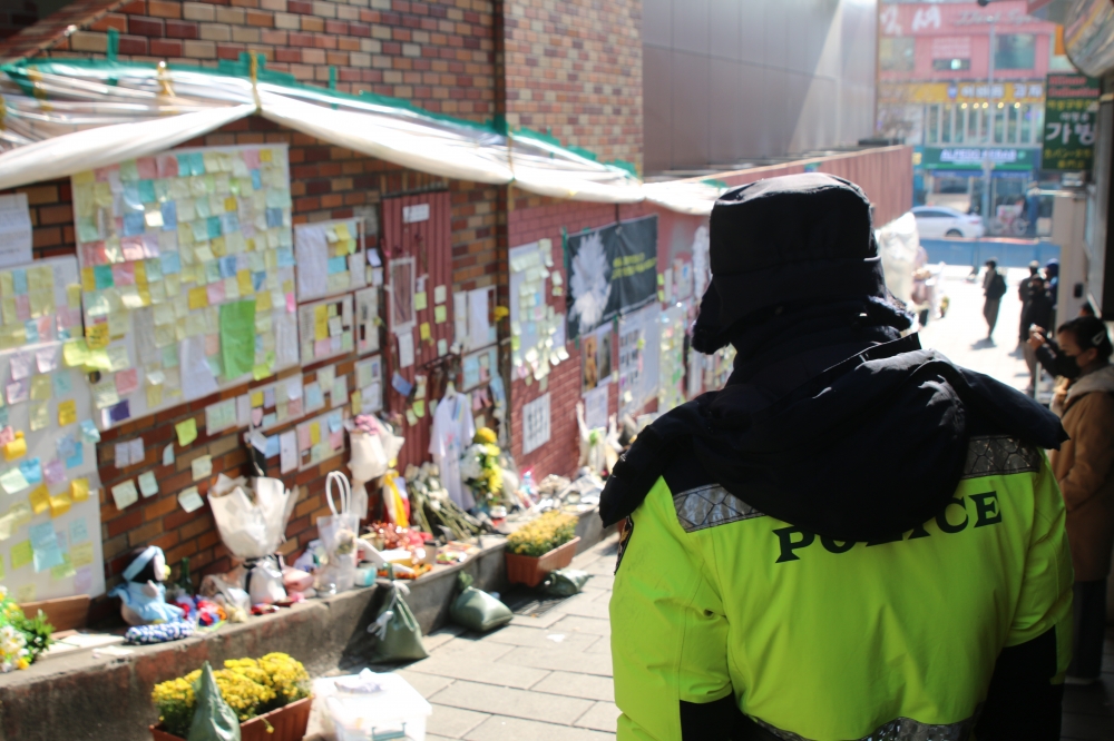 사진 설명 시작. 사고가 일어난 이태원 골목을 바라보는 경찰의 뒷모습. 고개를 숙이고 땅을 바라보고 있다. 사진 설명 끝.
