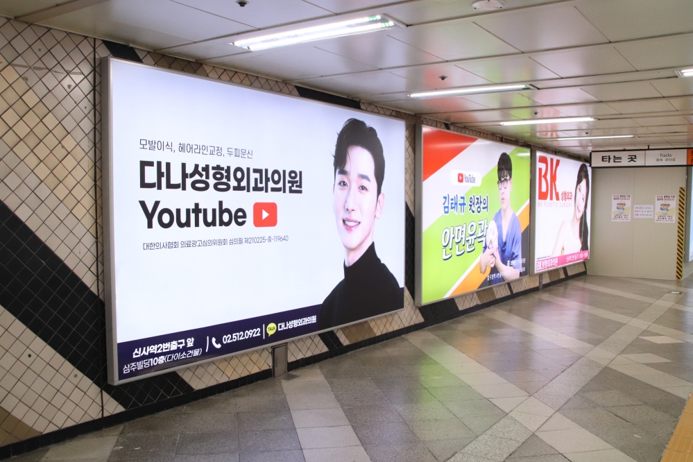 사진 설명 시작. 왼쪽부터 세 개의 화려한 성형 광고가 모두 큰 전광판에 나란히 게시돼 있다. 사진 설명 끝.