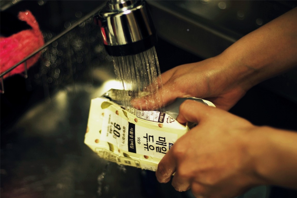 사진 설명 시작. 두유팩 내부를 물로 씻고 있다. 사진 설명 끝.