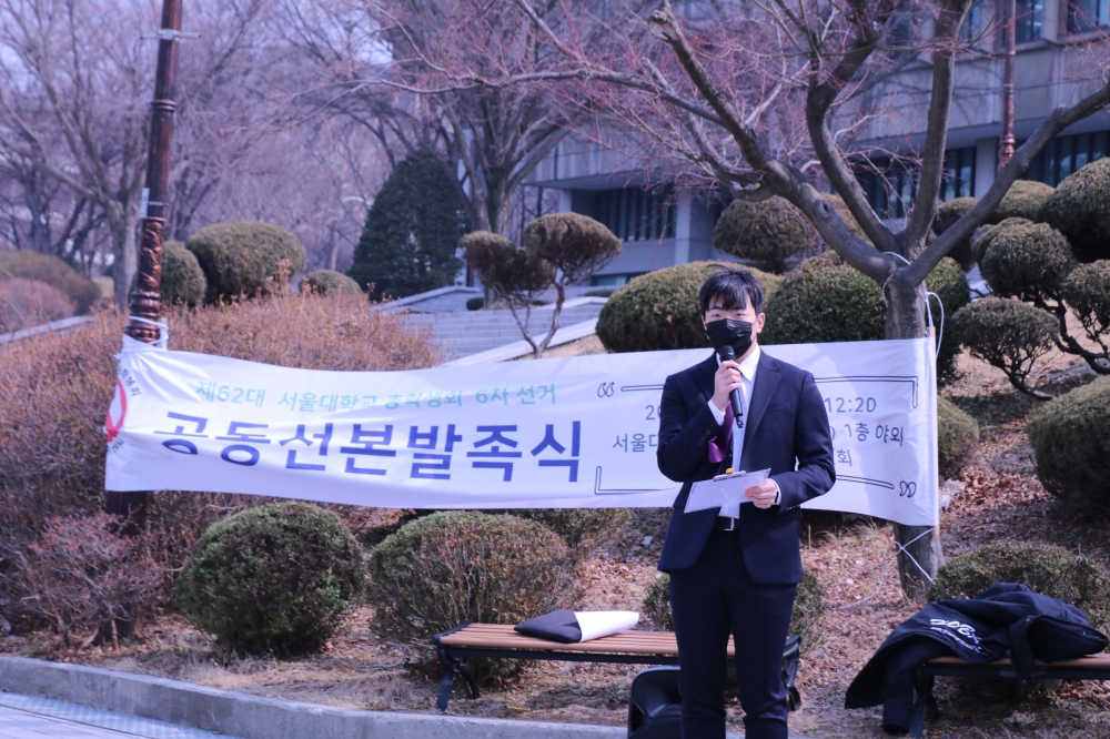 사진 설명 시작. 학생회관 앞에서 전현철 부후보가 발언하고 있다. 공동선본발족식 현수막이 뒤에 걸려있다. 사진 설명 끝.