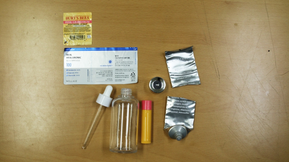 사진 설명 시작. 분리배출을 위해 화장품 라벨, 깨끗하게 씻긴 앰플 통, 립밤 통, 수분 크림 튜브가 책상 위에 따로 놓여 있다. 사진 설명 끝.